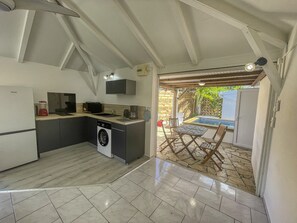 A compact kitchen with a built-in washer, a dining area with a table and chairs, and a view of the outside. - Charming villa with pool - 2 guests (Saint-François)
