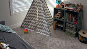 Une salle de jeux pour enfants avec un tipi, une bibliothèque et un miroir.