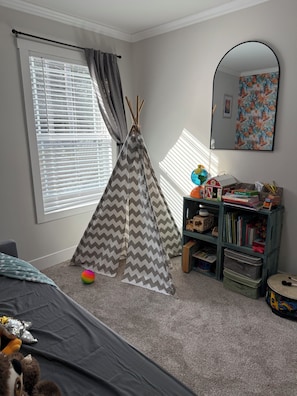 A child's playroom with a teepee, a bookshelf, and a mirror.
