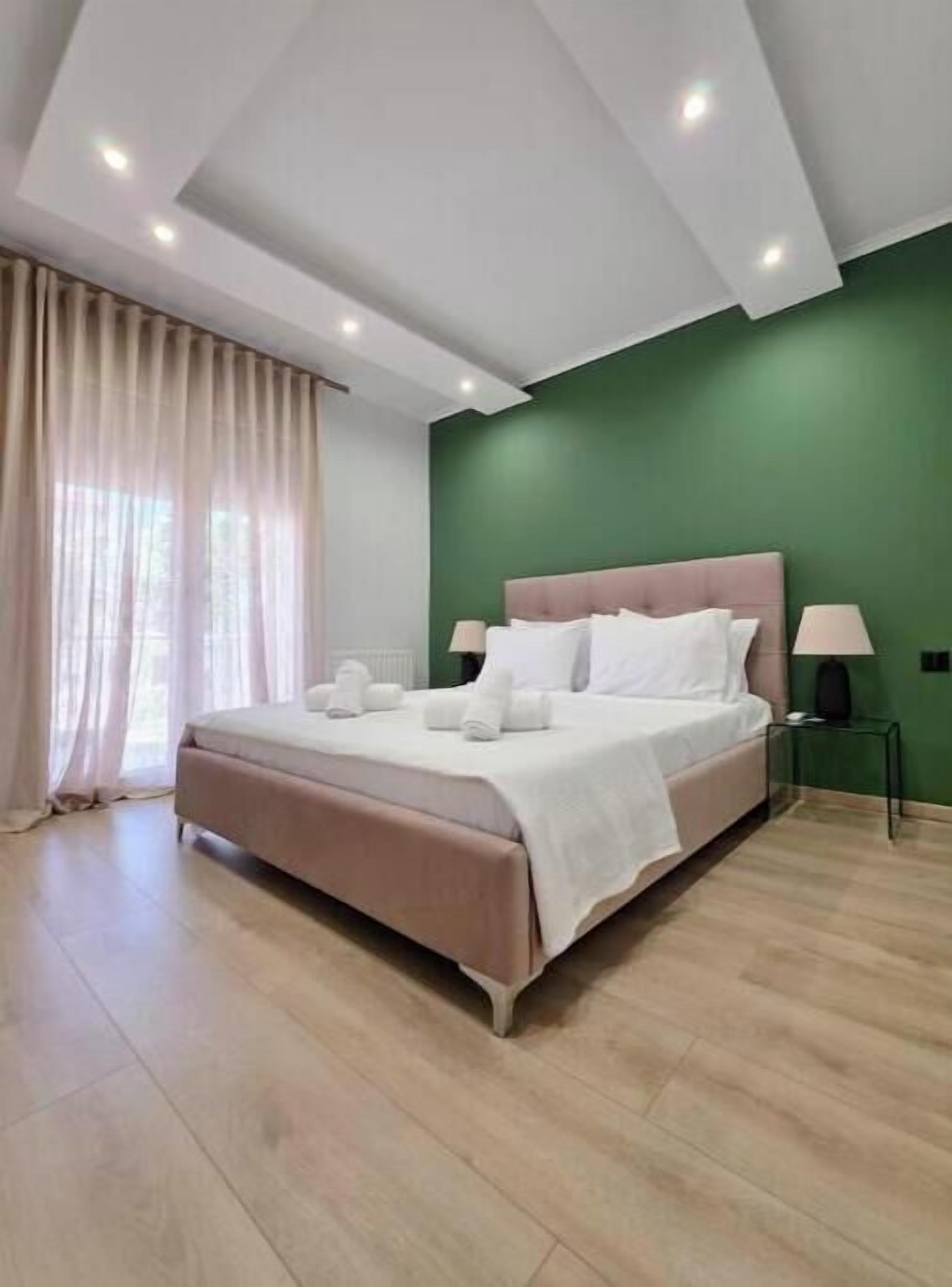 Une chambre moderne avec un grand lit, un mur d’accent de couleur verte et un plancher en bois.