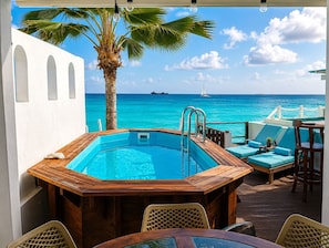An outdoor swimming pool with a wooden deck, lounge chairs, and a view of the ocean. - Waterfront Paradise 4 bedroom Villa SXM (Koolbaai)