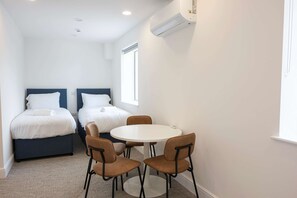 Habitació d'hotel petita amb dos llits, una taula rodona i quatre cadires.