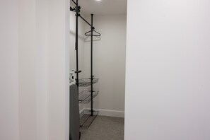 A corner of a room with a black metal shelving unit against a white wall, featuring multiple shelves and hooks. - The Maycliffe - Large Studio Apartment nr Harbor (Torquay)