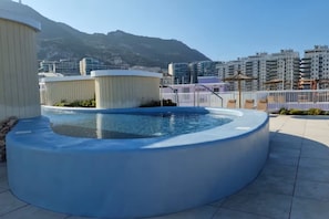 Una piscina al terrat amb vistes a una muntanya i edificis de la ciutat.
