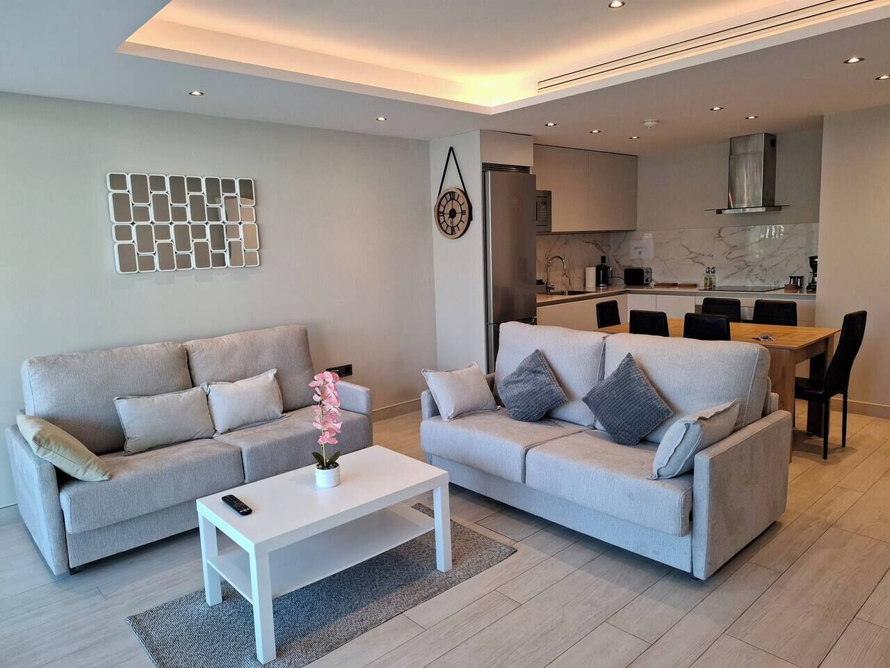 A modern living room with two sofas, a coffee table, and a dining area with a table and chairs.