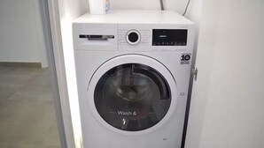 A front-loading washing machine with a digital display and a control panel. - Luxury Marina Resort | Rock Views & Pools - Apartment (Gibraltar)