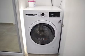 A front-loading washing machine with a digital display and a control panel. - Luxury Marina Resort | Rock Views & Pools - Apartment (Gibraltar)