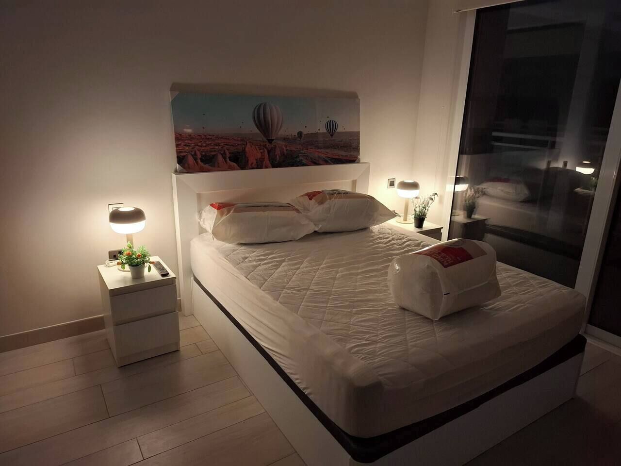 Un dormitorio moderno con una cama, mesitas de noche y un cuadro en la pared.