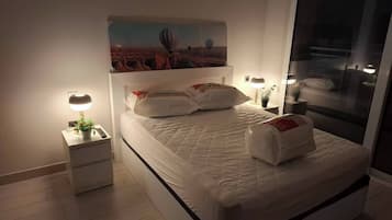 Un dormitorio moderno con una cama, mesitas de noche y un cuadro en la pared.