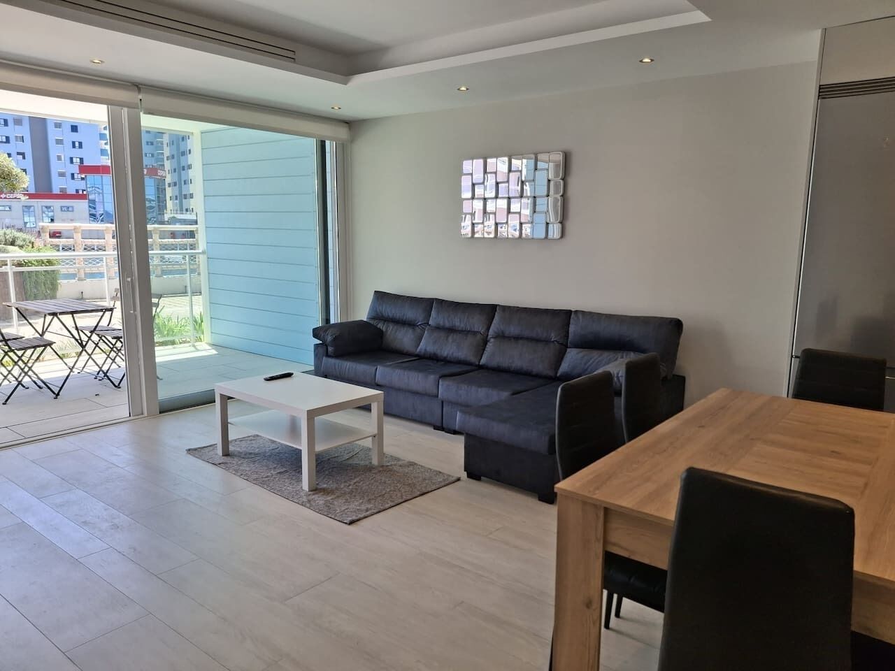 A modern living room with a sofa, a coffee table, and a dining table.