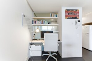 A compact office space with a desk, chair, computer, and shelves with books. - Lake View 1-bed Apartment Canberra Centre (Canberra)