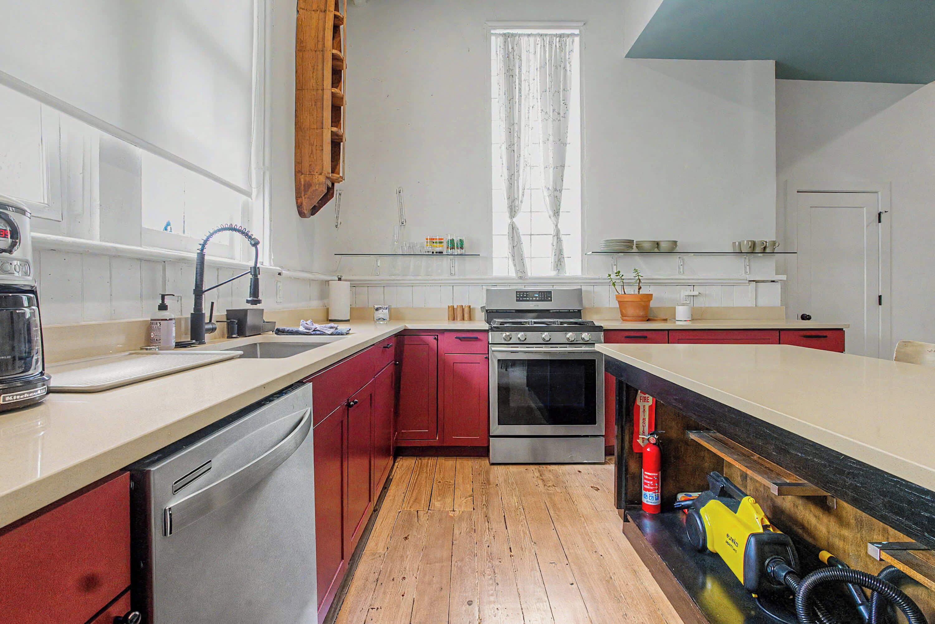Une cuisine équipée d’une cuisinière, d’un évier et d’un plancher en bois.