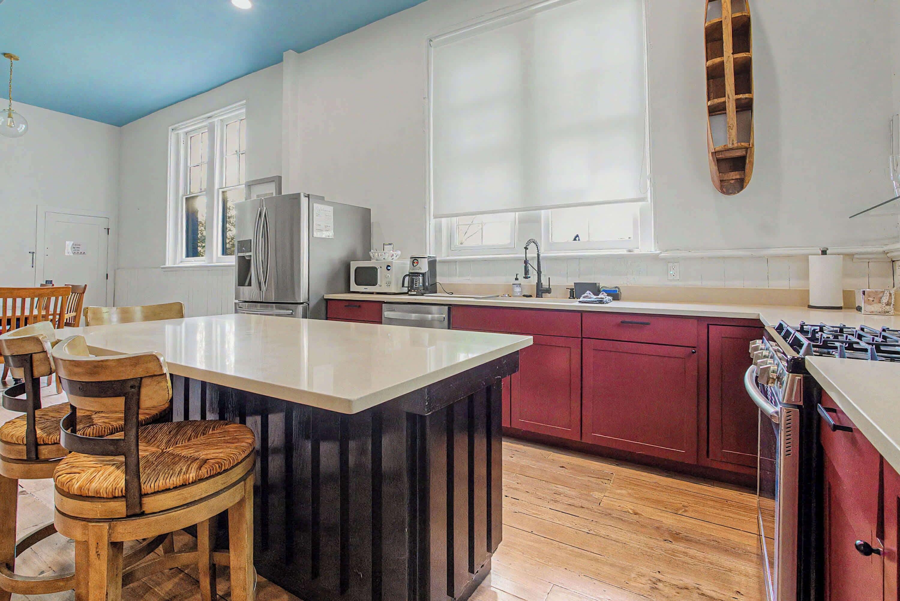 A kitchen with a central island, wooden chairs, a refrigerator, a microwave, and a stove.