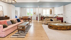 Ein großzügiges Wohnzimmer mit einem gestreiften Sofa, einem Couchtisch und einem Essbereich mit Stühlen.