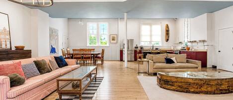A spacious living room with a striped sofa, a coffee table, and a dining area with chairs.