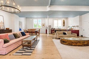 Ein großzügiges Wohnzimmer mit einem gestreiften Sofa, einem Couchtisch und einem Essbereich mit Stühlen.