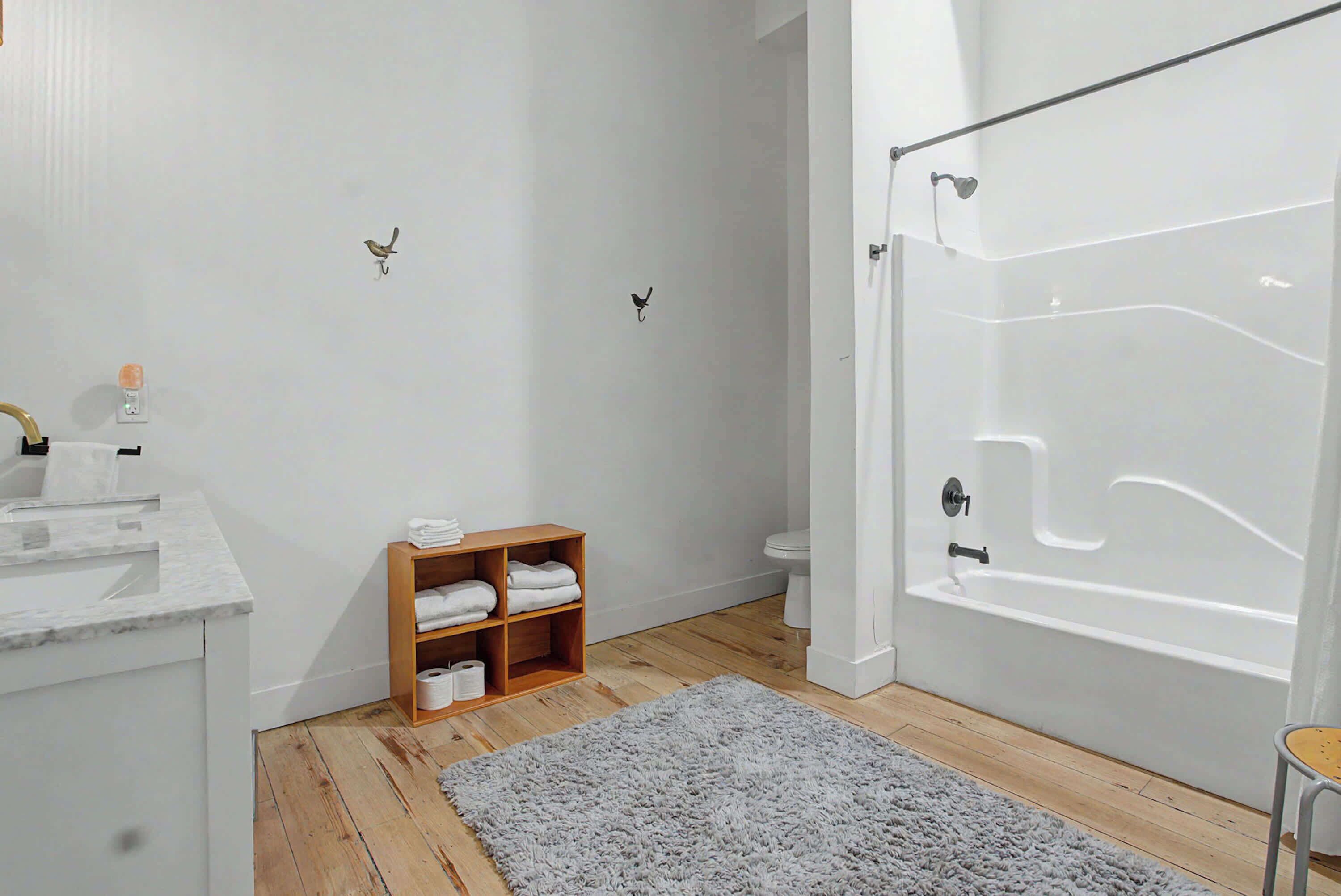 A bathroom with a bathtub, toilet, and a wooden shelf with towels.