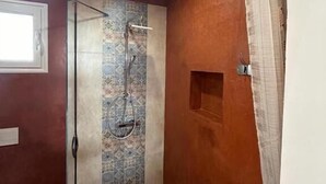 Een badkamer met een douche, een raam en een deur.