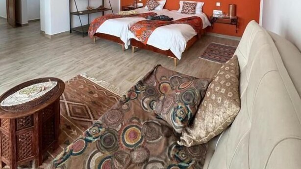 Een slaapkamer met een bed, een bank, een salontafel en een vloerkleed.