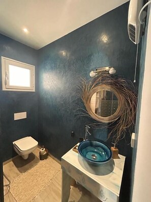 Un baño con un lavabo azul, un inodoro blanco y un espejo con un marco decorativo.