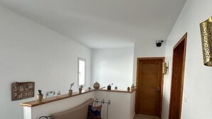 Een gang met een bank, een deur en een wandlamp.