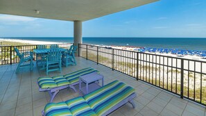 Ein Balkon mit Blick auf den Strand, ausgestattet mit Liegestühlen und einem Tisch.