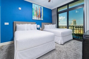 Ein Hotelzimmer mit zwei Betten, einem großen Fenster und Blick auf die Stadt sowie einem Bild an der Wand.