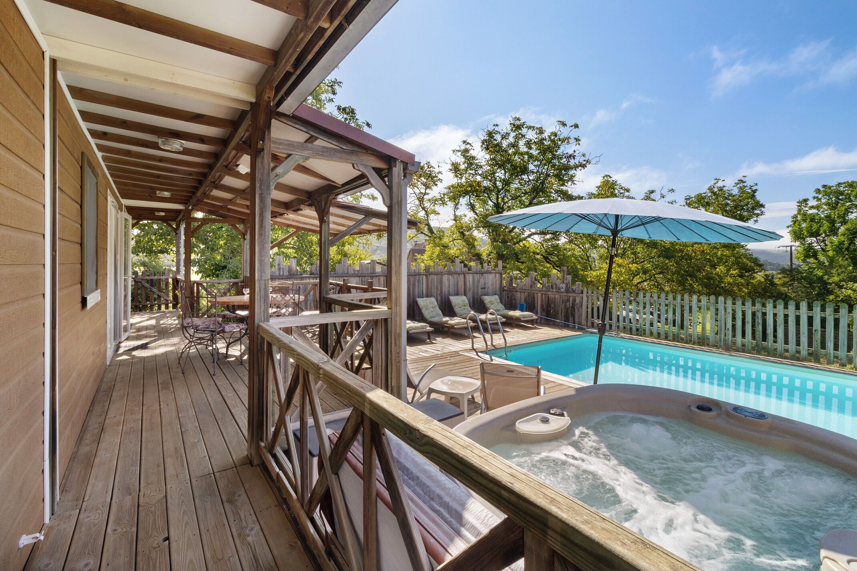 Een houten terras met buitenmeubilair, een jacuzzi en een zwembad.
