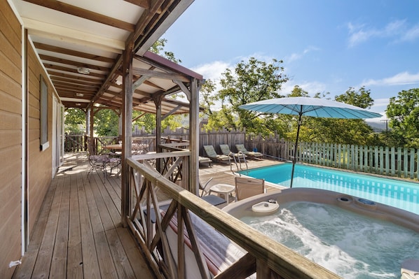 A wooden deck with outdoor furniture, a hot tub, and a swimming pool.
