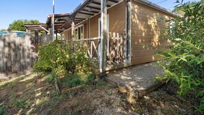 Une structure en bois surmontée d’un toit en métal, entourée d’une clôture en bois, et accessible par un chemin de gravier.