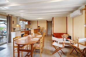 Une cuisine moderne avec des meubles en bois, un coin repas avec une table et des chaises en bois, et un coin salon confortable avec un canapé rouge.