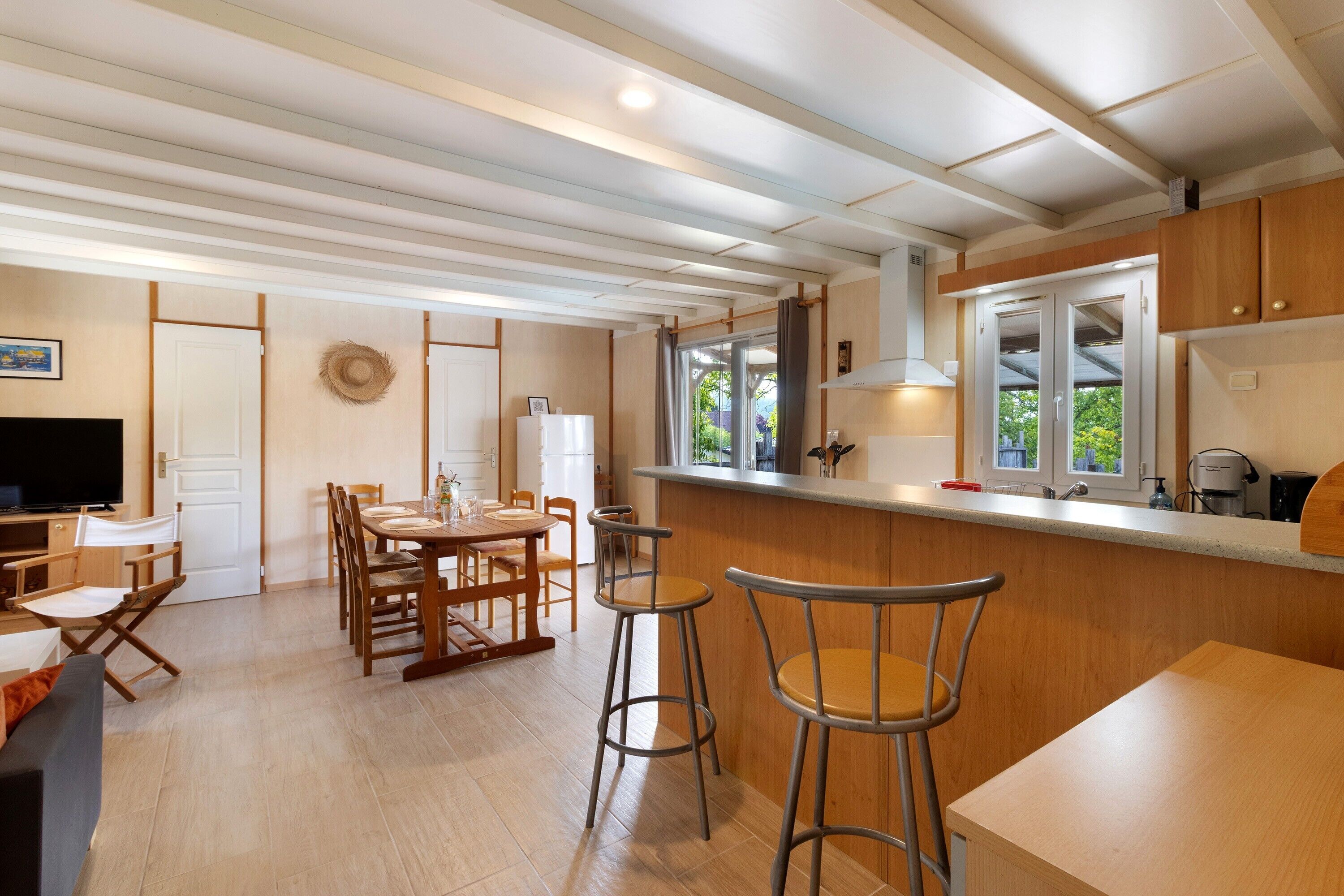 Een moderne keuken met een bar, houten kasten en een eethoek.
