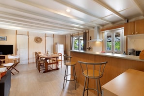 A modern kitchen with a bar area, wooden cabinets, and a dining set.