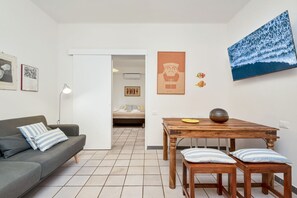 Ein modernes Wohnzimmer mit einer Couch, einem Esstisch mit Bänken und einem großen Gemälde an der Wand.