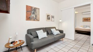 A modern living room with a grey sofa, striped pillows, a coffee table with a tray of items, and artwork on the wall. - [CasaSolemare] Terrace+seaview+A/C (Porto Venere)