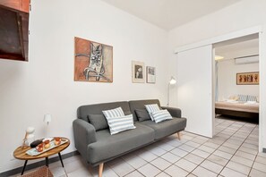 Ein modernes Wohnzimmer mit einem grauen Sofa, gestreiften Kissen, einem Couchtisch mit einer Auflage und Kunstwerken an der Wand.