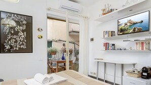 A hotel room with a bed, a TV, a bookshelf, and a view of the outdoors. - [CasaSolemare] Terrace+seaview+A/C (Porto Venere)