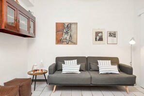 Ein modernes Wohnzimmer mit einem grauen Sofa, gestreiften Kissen und einem kleinen runden Tisch mit einer Tablett-Anordnung.