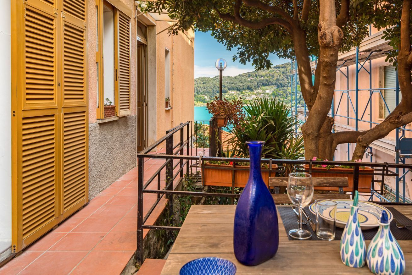 Eine Terrasse mit Esstisch, einer blauen Vase und Blick auf einen Hügel.