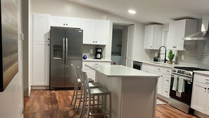 Eine moderne Küche mit weißen Schränken, einem Edelstahlkühlschrank, einem eingebauten Backofen und Holzboden.