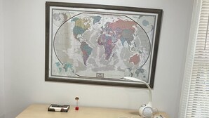 Ein Arbeitszimmer mit Schreibtisch, Stuhl und einer Weltkarte an der Wand.