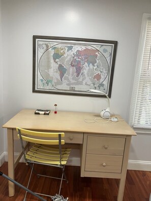 Ein Arbeitszimmer mit Schreibtisch, Stuhl und einer Weltkarte an der Wand.