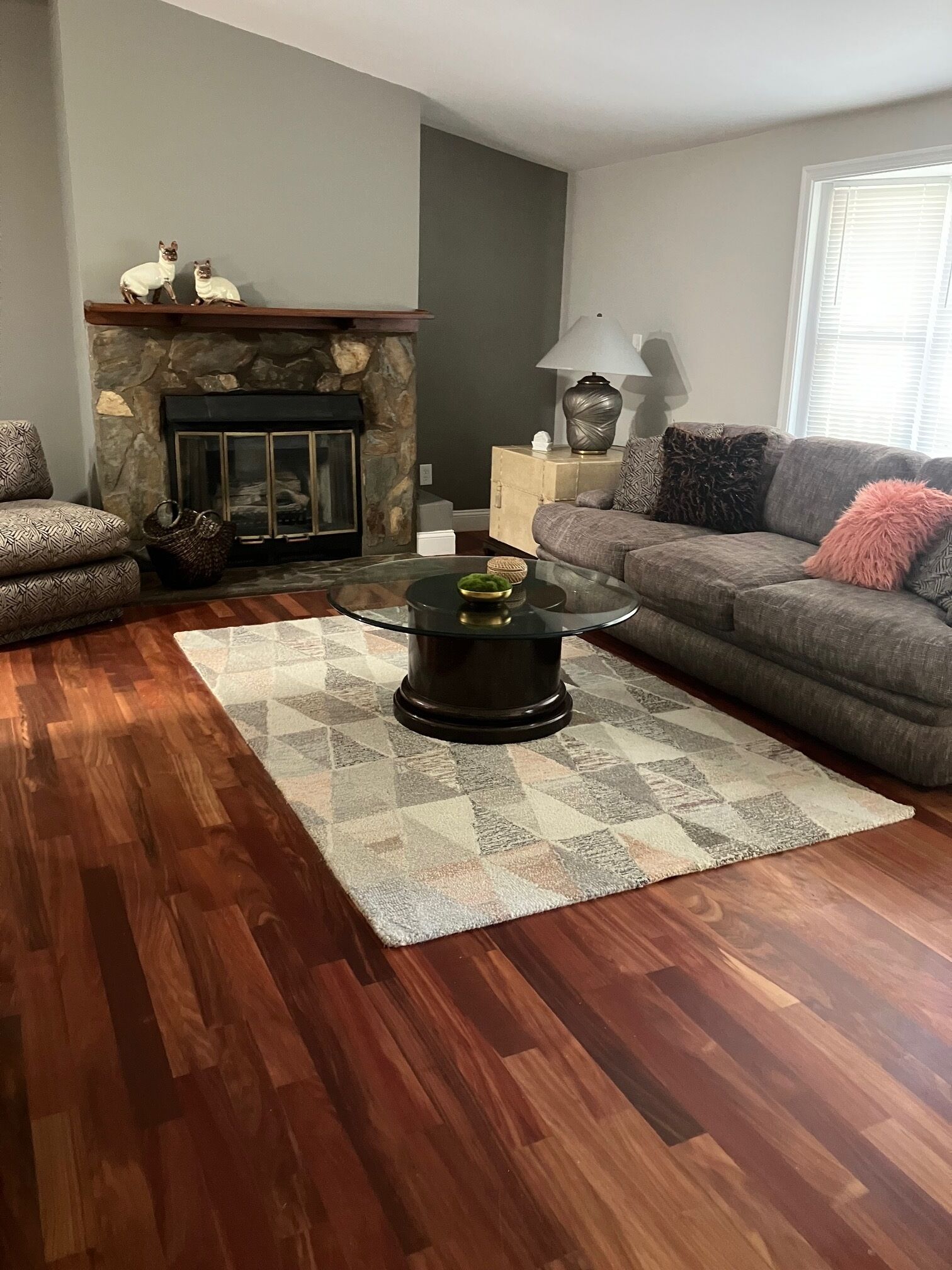 Una sala de estar con chimenea, una mesa de centro de vidrio, un sofá y un tapete estampado.