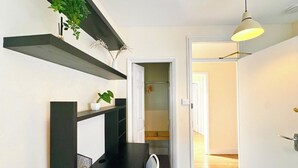 A hallway with a desk, chair, and a hanging plant. There is a door leading to another room. - Contractor Stay | 3 Bedrooms | Long Stays Welcome (Southampton)