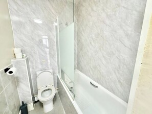 Ein Badezimmer mit Toilette, einer Glasdusche und einer Badewanne.