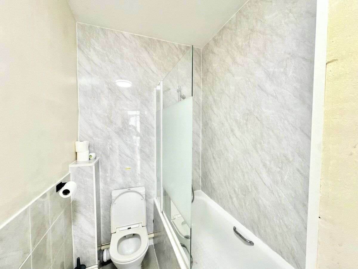 A bathroom with a toilet, a glass shower enclosure, and a bathtub.