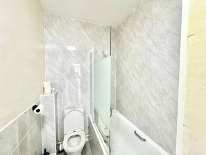 Ein Badezimmer mit Toilette, einer Duschkabine aus Glas und einer Badewanne.