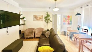 A living room with a sofa, two armchairs, a dining table with chairs, a flat-screen TV mounted on the wall, and a ceiling light fixture. - Contractor Stay | 3 Bedrooms | Long Stays Welcome (Southampton)