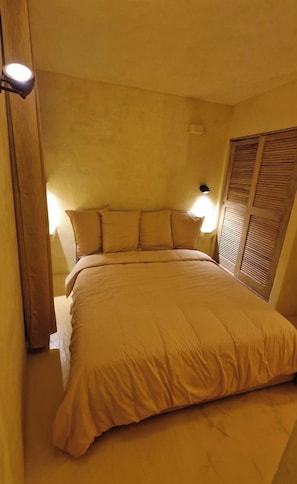 Un dormitorio pequeño y acogedor con una cama individual, una mesita de noche y una lámpara de pared.