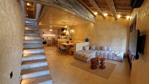 A spacious interior with a staircase leading to a kitchen area, a seating area with a sofa and a coffee table, and a television mounted on the wall. - Casa Solea - Gulf of Saint-Tropez (Le Plan-de-la-Tour)